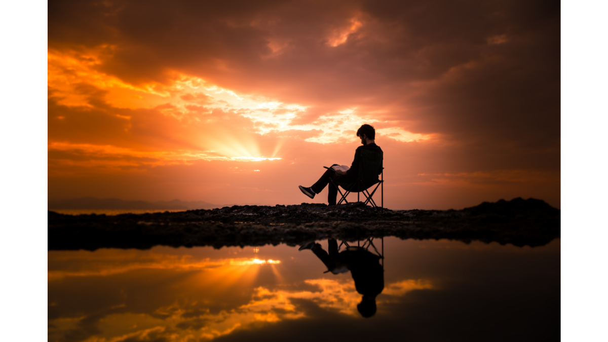 海の前で夕日に向かって椅子に座っている人